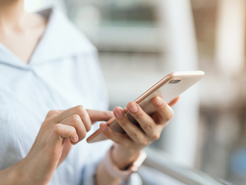 Frauenhände, die auf goldenes Smartphone tippen